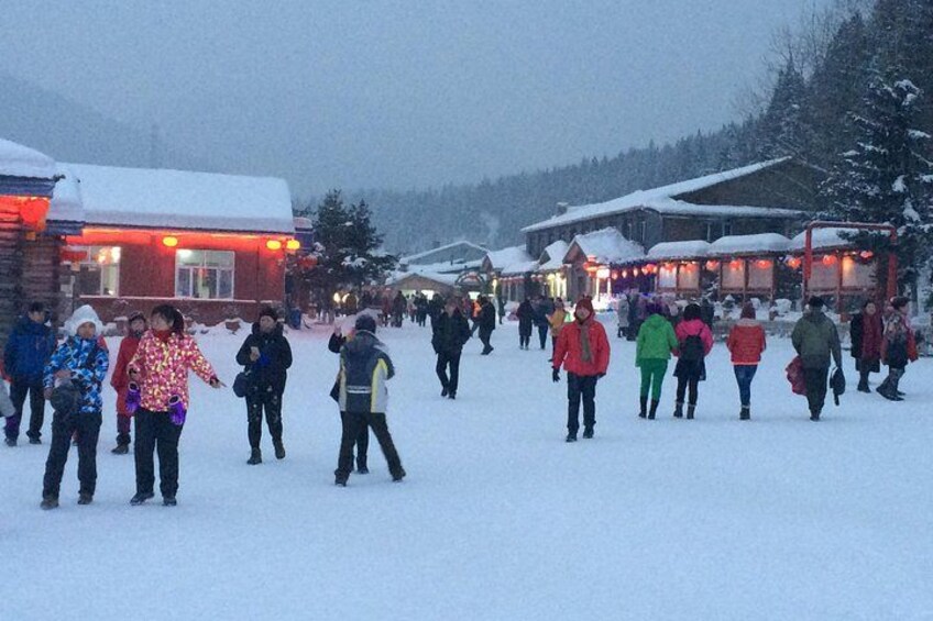 A snowy outdoor market with people walking and buildings with snow-covered roofs. 3