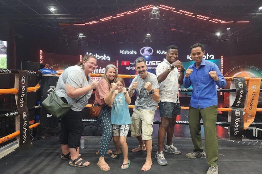 A group of people posing in a boxing ring with boxing gloves and a referee's outfit. 2