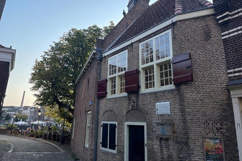 A brick building with a white door, a window with a shutter, and a sign on the wall. 5