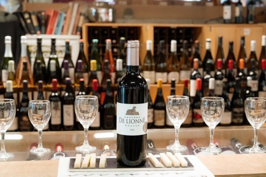 A wine tasting setup with a bottle of De Lionne wine, glasses, and a selection of cheese. 3