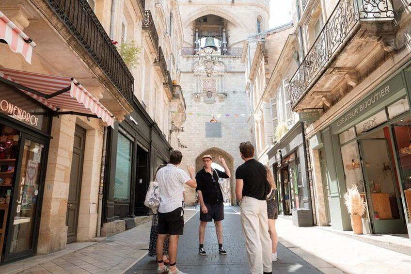 A narrow street with shops on either side, a pedestrian, and a building with a balcony. 3