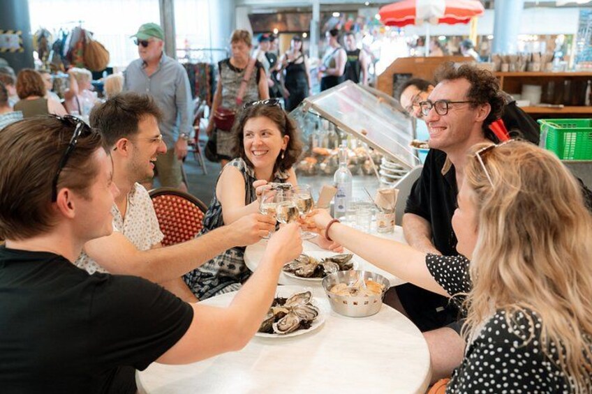 A group of people toasting at a table in a busy indoor market. 2