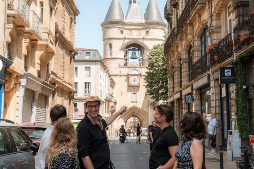 A group of people standing on a street with historic buildings and a prominent tower in the background. 2