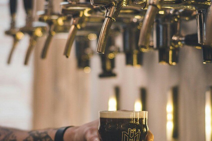A hand holding a glass of beer with a tap in the background. 4