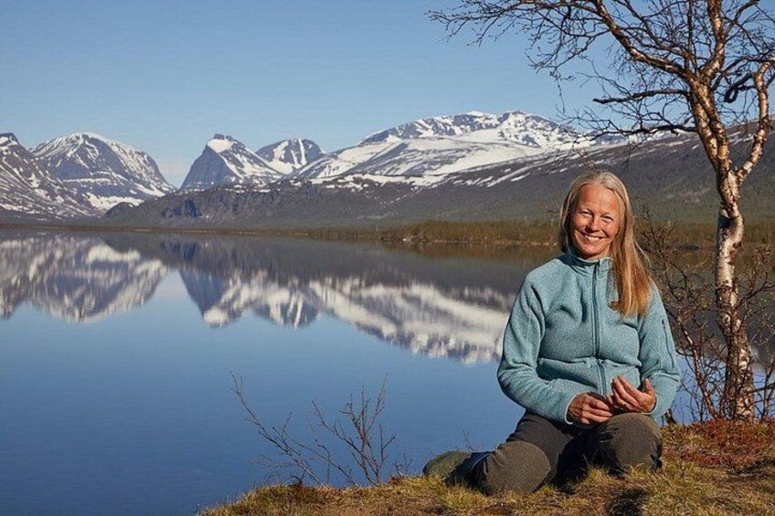 Une personne assise au bord d’un lac, avec des montagnes en arrière-plan. 1