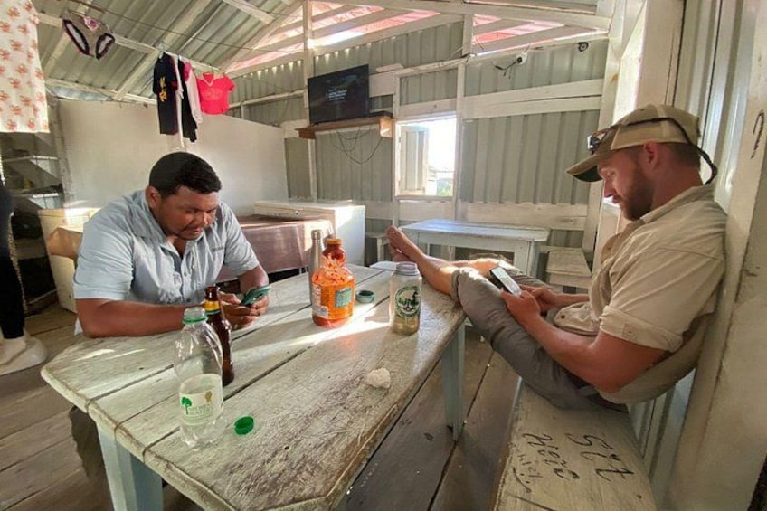 Two men sitting at a wooden table in a rustic kitchen, one holding a smartphone. 5
