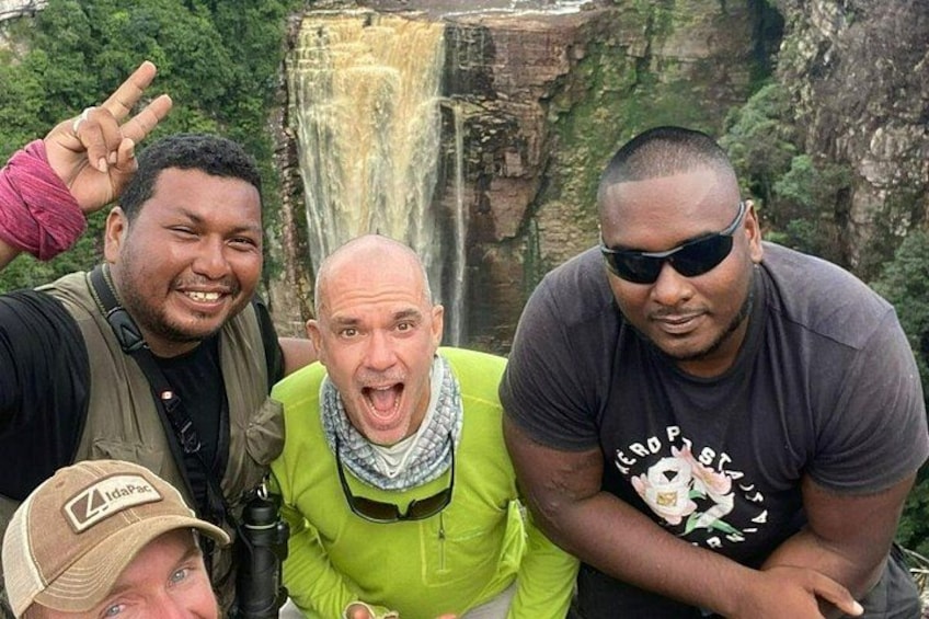 A group of people near a waterfall with a rocky cliff in the background. 3
