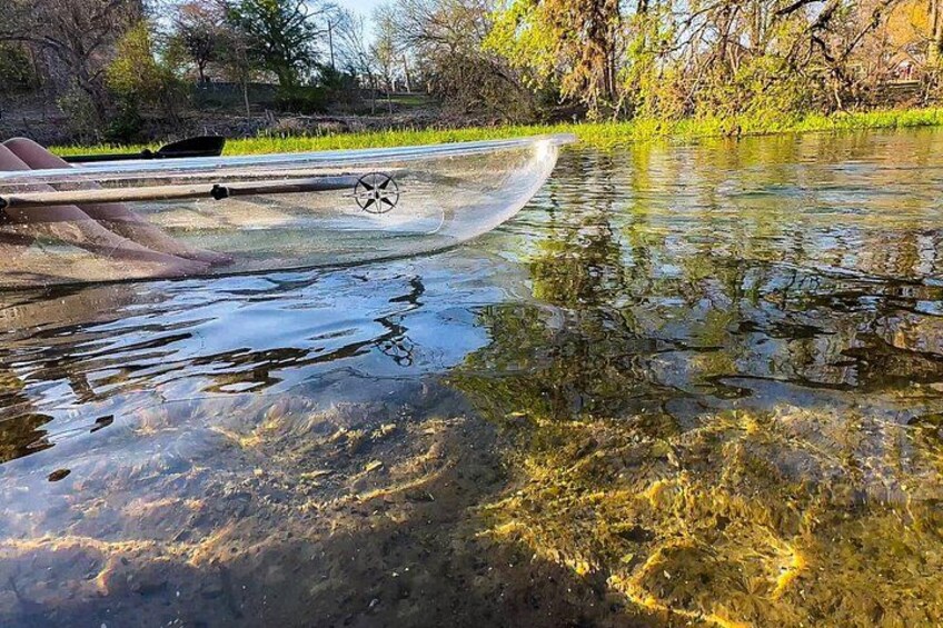 A kayak on a calm river with reflections of trees and a grassy bank. 3