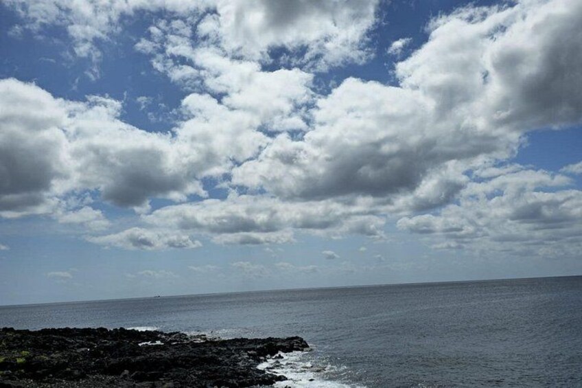 A coastal landscape with a rocky shoreline, ocean, and a partly cloudy sky. 2