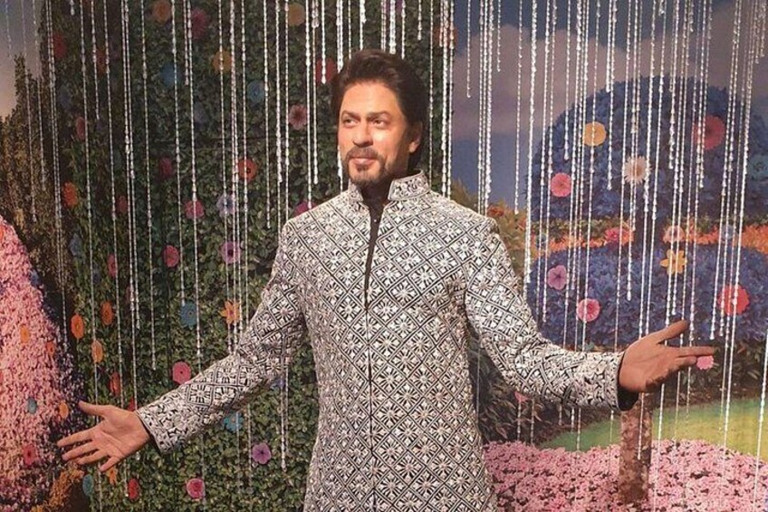 A person in a patterned outfit standing in front of a floral backdrop. 3