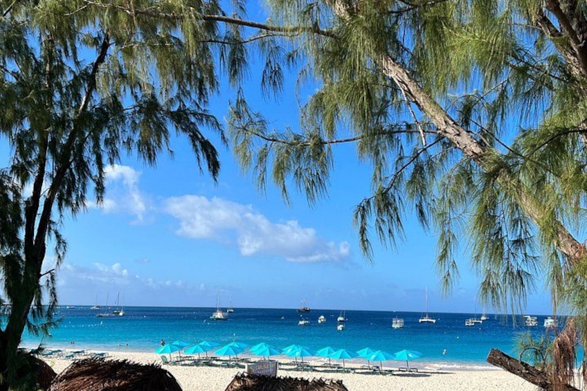 A beach with clear blue water, boats, and umbrellas. 5