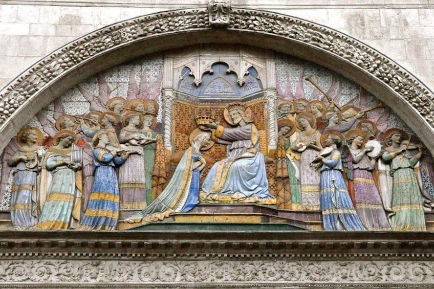A detailed stone relief with a central figure in blue and gold, surrounded by figures in colorful robes. 2
