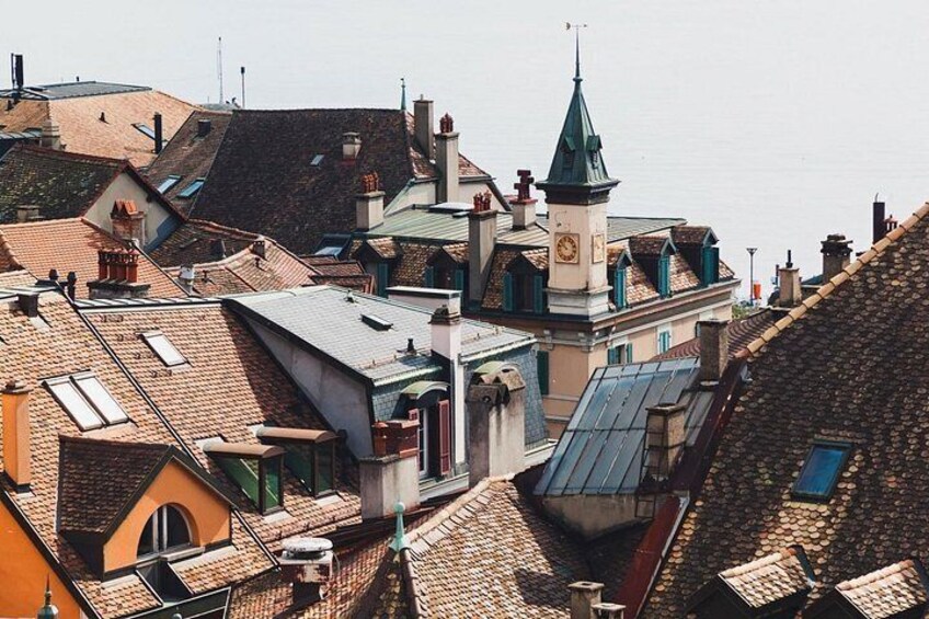 A densely packed urban area with a variety of rooftops, including sloped and flat sections, and a prominent church with a spire. 2