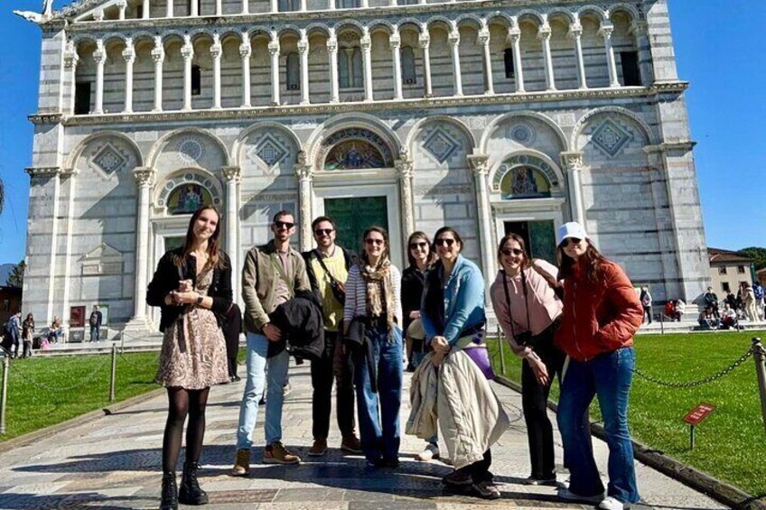 A group of people posing in front of a large, ornate building with columns and arches. 3