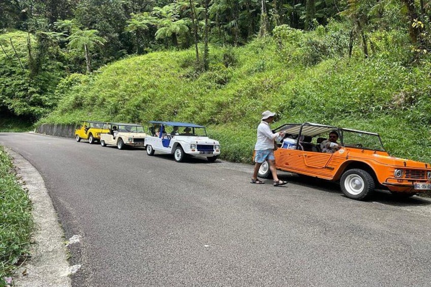 A road with a white car and an orange car parked on the side. 2