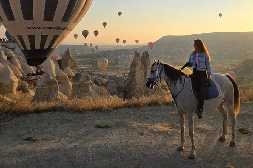 Una persona monta a caballo cerca de globos aerostáticos en un paisaje rocoso. 5