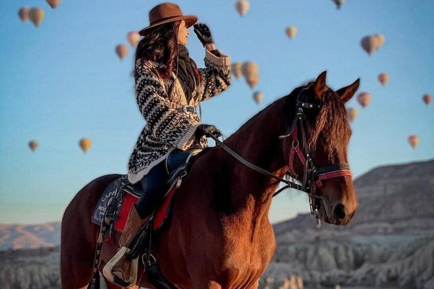 Una persona montando a caballo con globos aerostáticos al fondo. 4