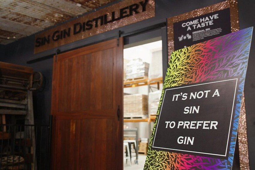 A gin distillery interior with wooden doors and a colorful sign. 1