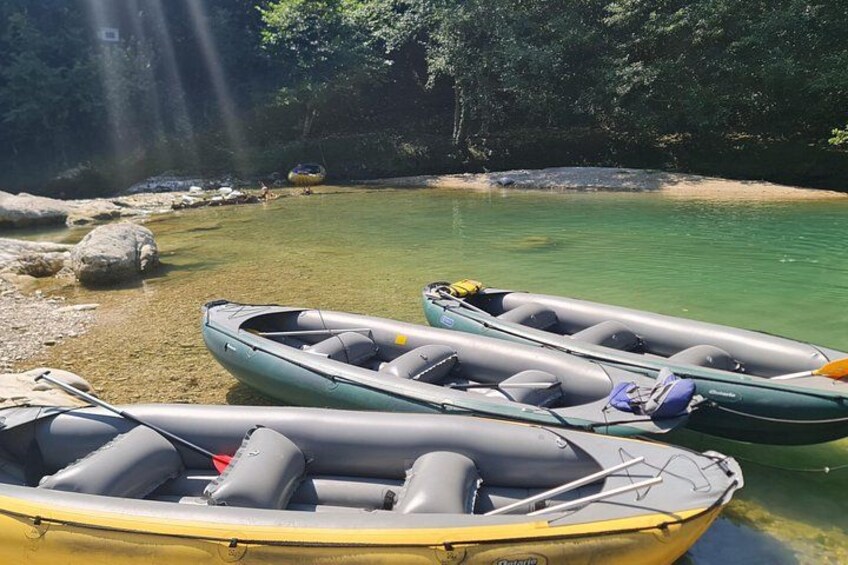 Trois bateaux pneumatiques sur une rive de rivière dégagée, avec des rochers et des arbres en arrière-plan. 5