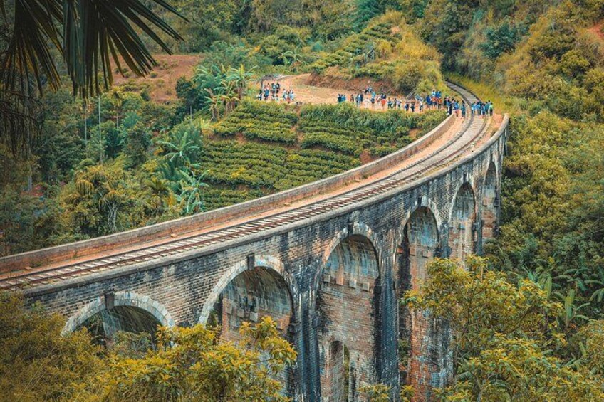 A long, arched stone bridge with people walking on it. 4