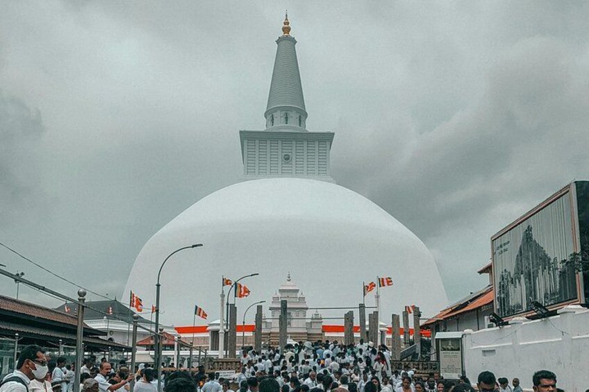 A large white dome structure with a spire, surrounded by a crowd of people. 3