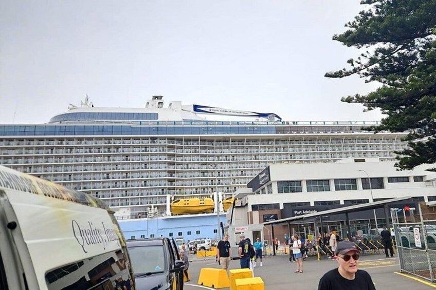A large cruise ship docked at a port with a terminal building in the foreground. 2