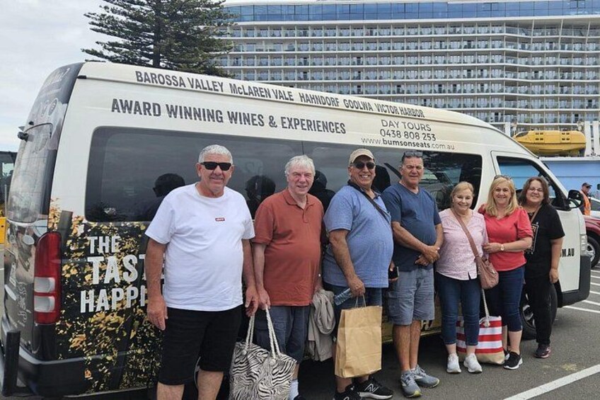 A group of people standing in front of a van with text advertising award-winning wines and experiences. 5