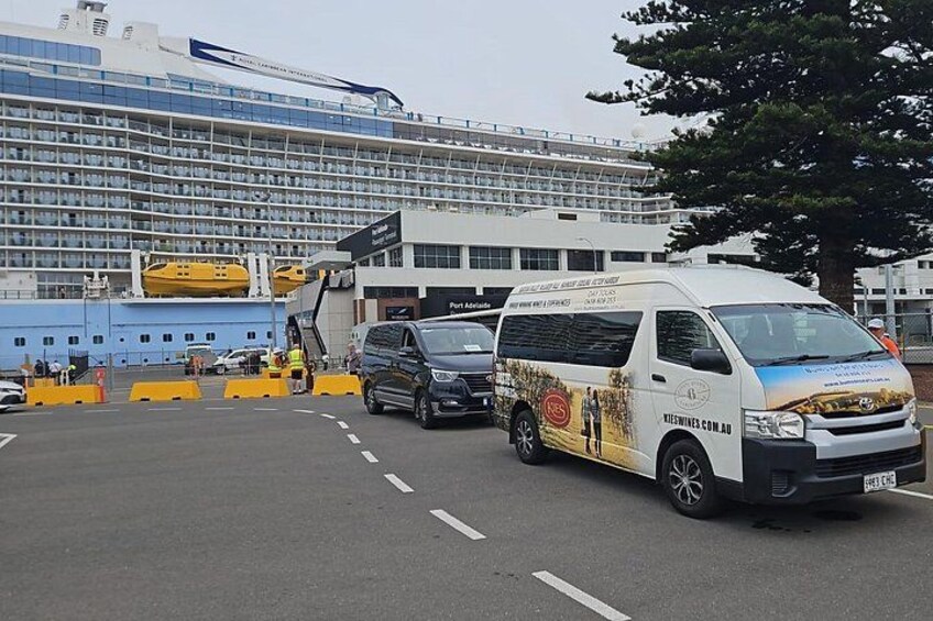 A cruise ship docked at a port with a white van parked in front. 3