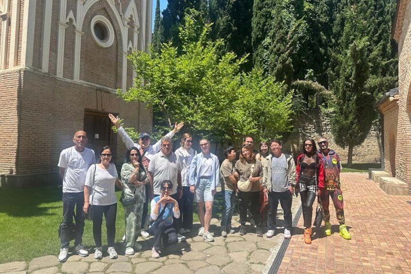 Un grupo de personas posando frente a una iglesia con fachada de ladrillo y ventanas de arco. 5