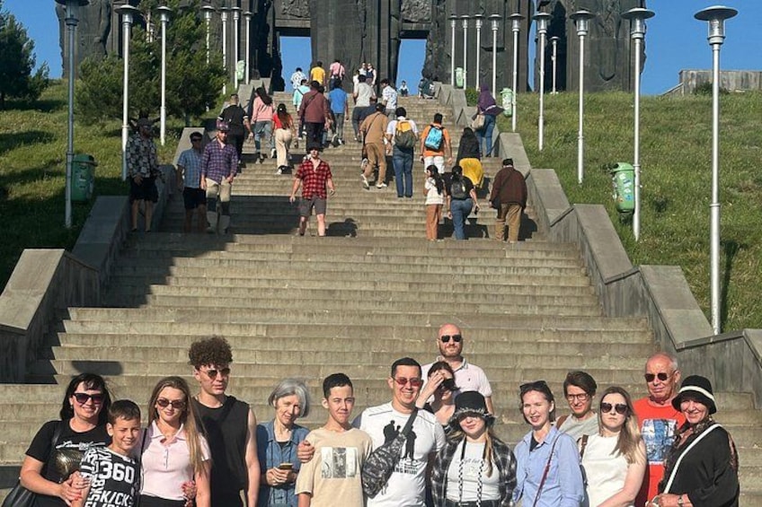 A group of people standing on a set of stairs with a monument in the background. 3
