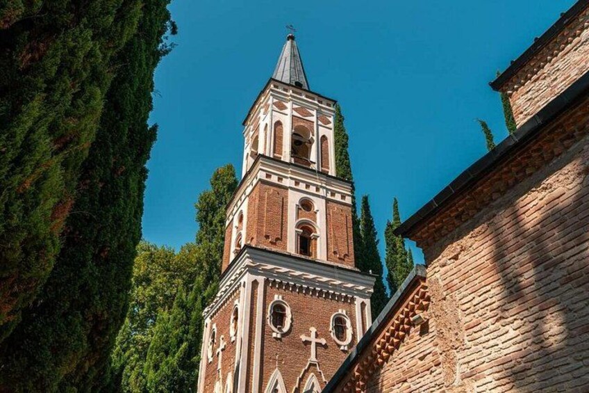 A church with a tall bell tower, brick walls, and a cross on the facade. 3