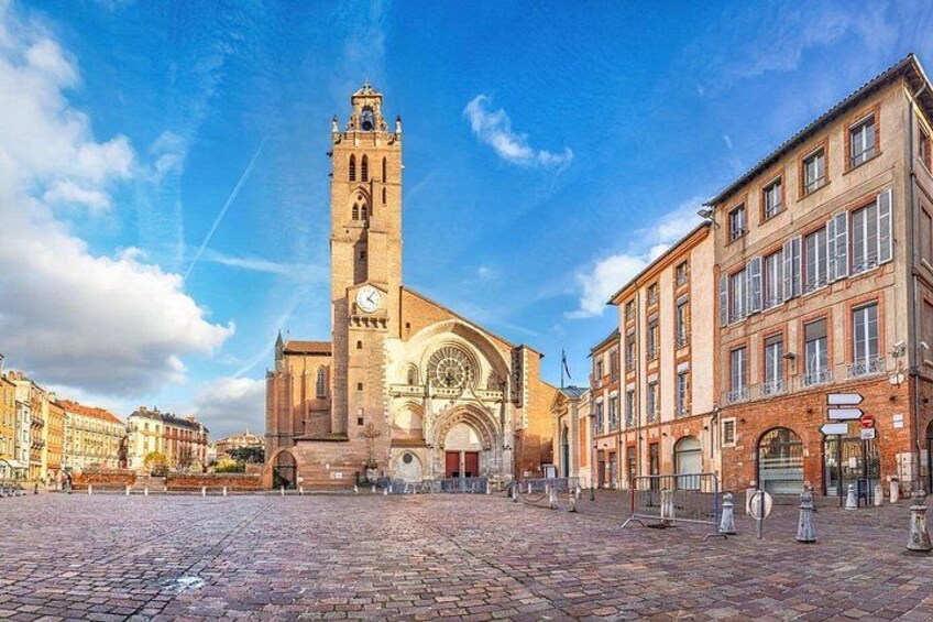 A historic church with a tall bell tower, cobblestone street, and surrounding buildings. 2