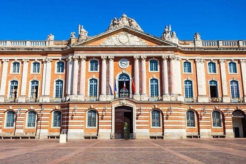 A large, historic building with a symmetrical facade, columns, and a central clock. 4