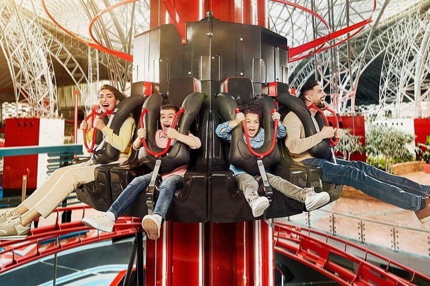 A roller coaster with passengers seated in the cars, a red track, and a metal structure in the background. 4