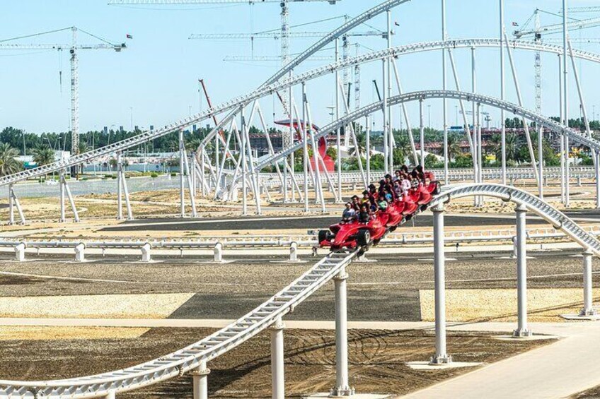 A red roller coaster in motion at an amusement park. 1