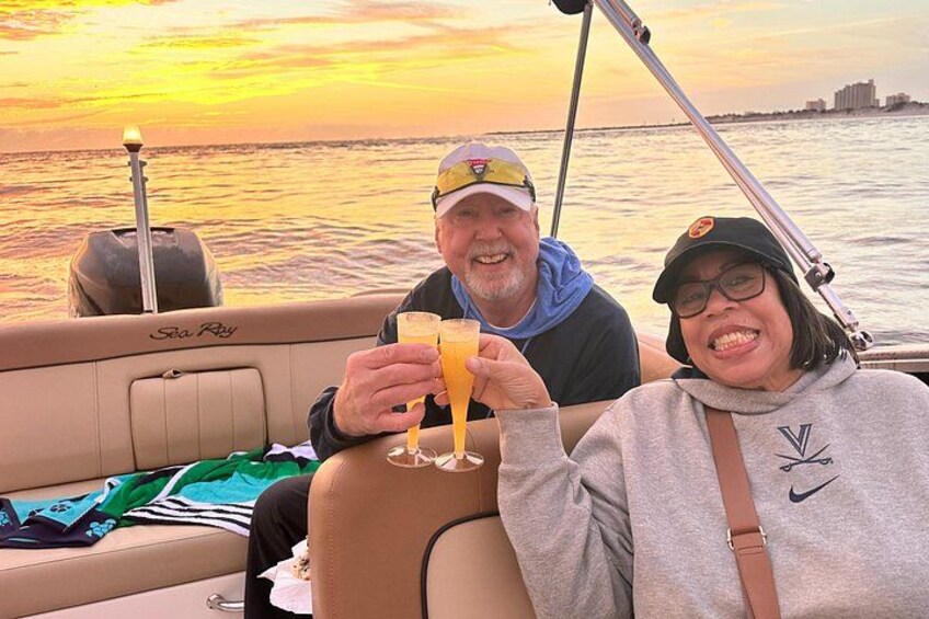 Dos personas en un bote, con bebidas, y una puesta de sol al fondo. 4