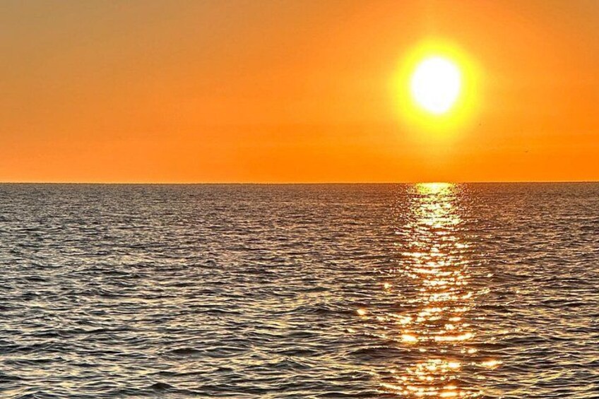 Un atardecer sobre un mar tranquilo con el sol reflejado en el agua. 5