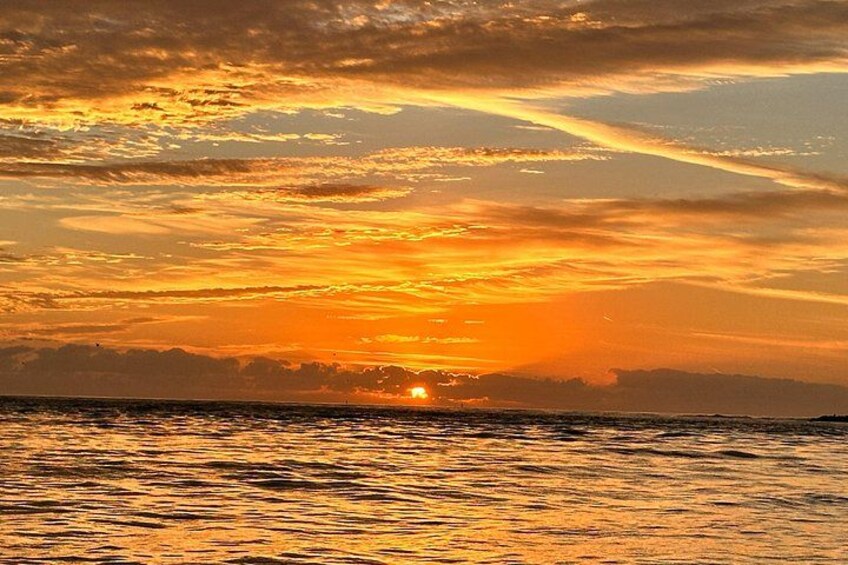 Atardecer sobre el océano con el sol visible cerca del horizonte y su reflejo en el agua. 3