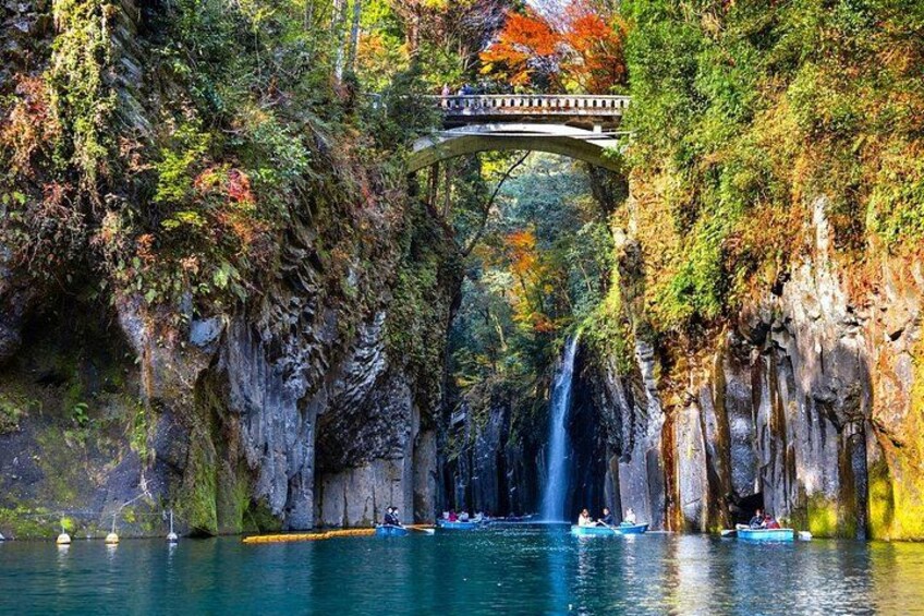 A bridge over a waterfall, surrounded by lush greenery and rocky cliffs. 1