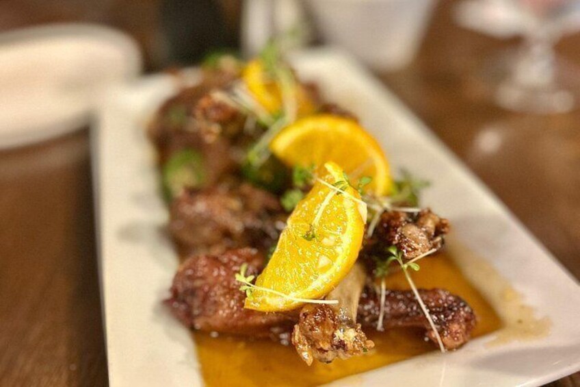 A dish with meat, orange slices, and greens on a white plate. 4