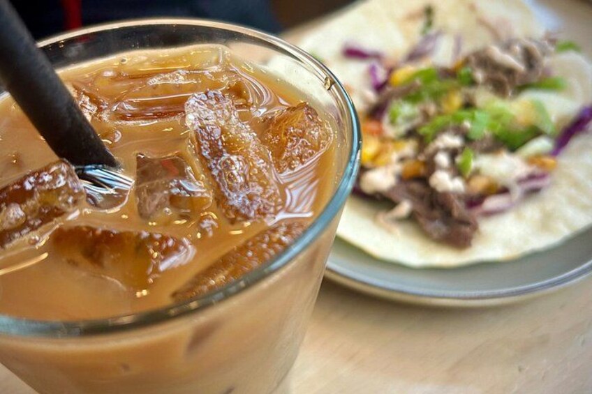 Un vaso de café helado con pajita y un plato de tacos con carne y verduras. 4