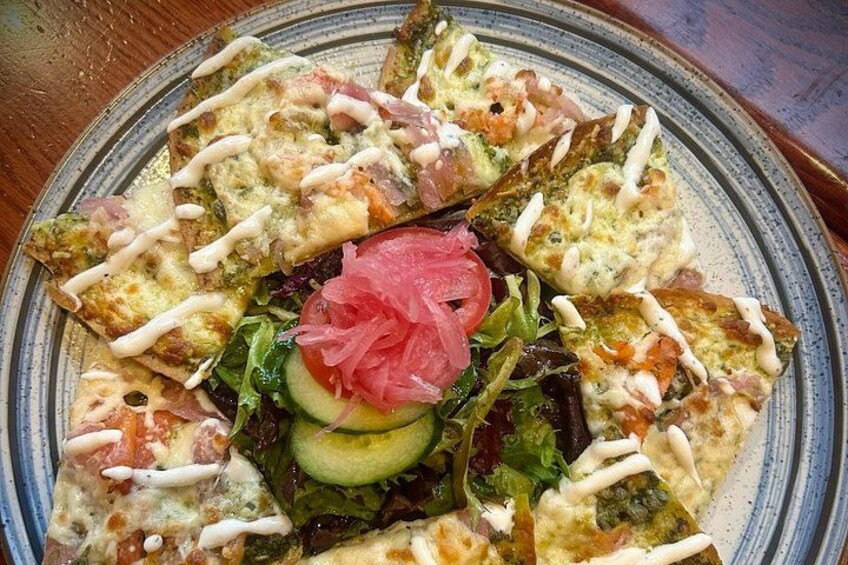 Un plato de pizza con ingredientes y una ensalada acompañante. 3