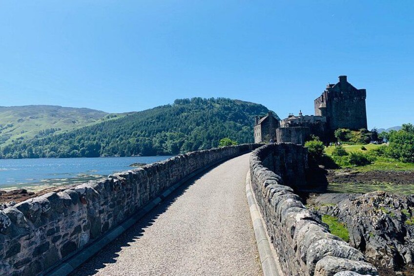 Ein gepflasterter Weg führt zu einer historischen Burg an einem See. 2