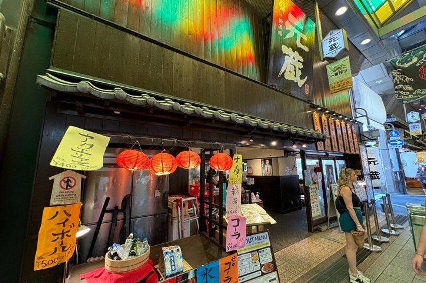 A traditional Japanese restaurant with a wooden exterior, red lanterns, and a signboard with Japanese characters. 4