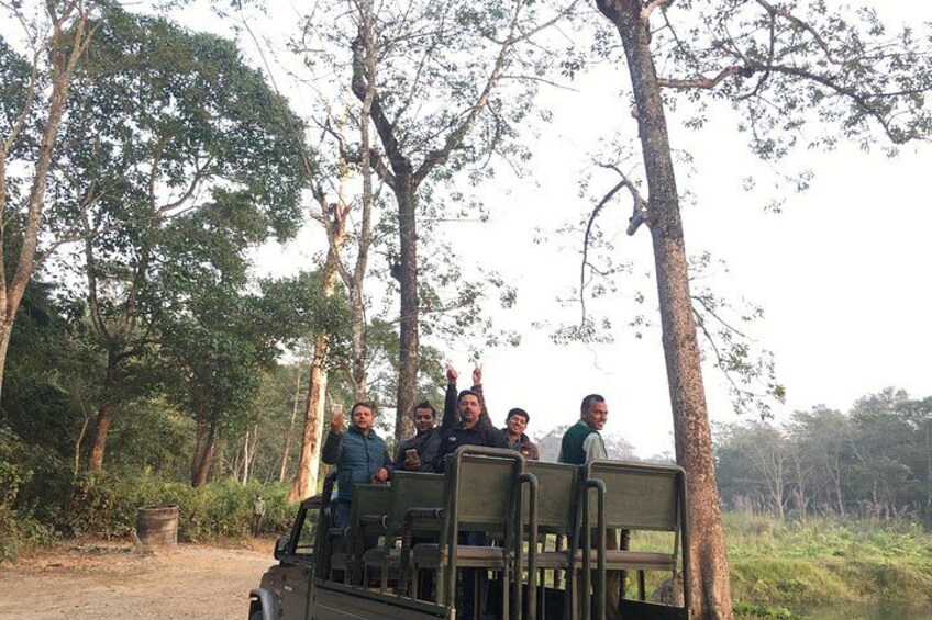 A group of people in a safari vehicle surrounded by trees in a natural setting. 2