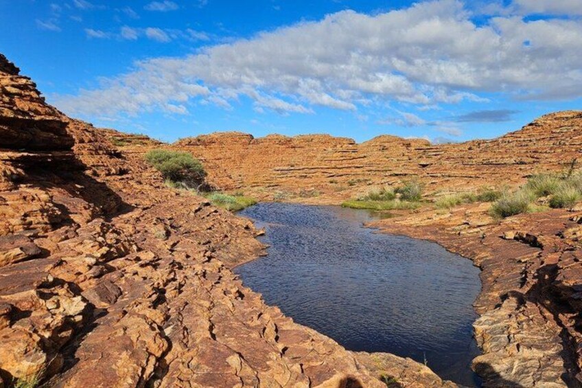 Un paisaje rocoso con una pequeña masa de agua rodeada de formaciones rocosas rojas. 3