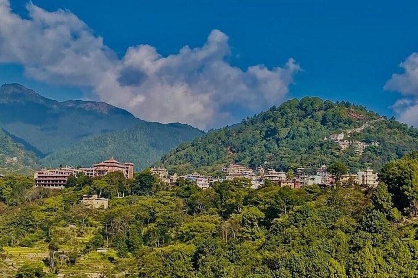 Paesaggio montuoso con una cittadina immersa tra le colline, caratterizzato da un edificio principale con tetto rosso. 3