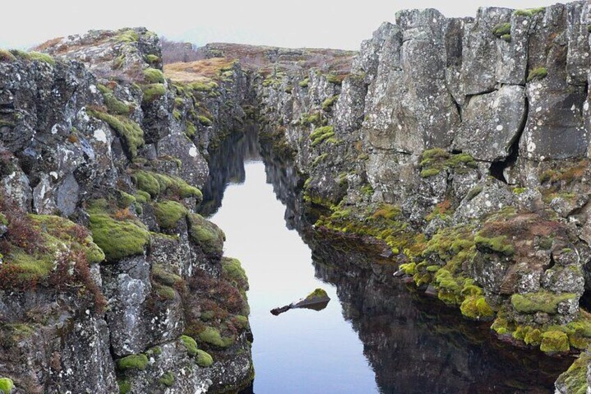 A narrow water channel flanked by rocky cliffs with patches of green moss. 5