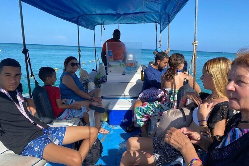 People on a boat with a blue canopy, ocean in the background. 3