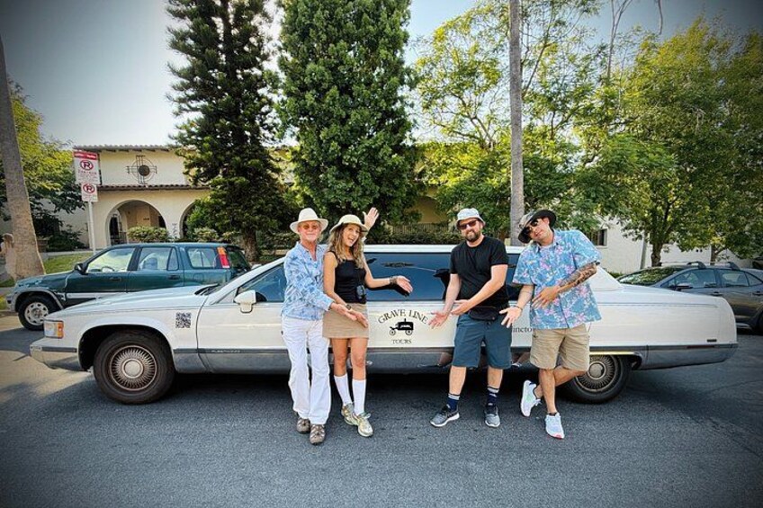 Un gruppo di persone in piedi davanti a un'auto bianca con un logo sul retro. 2